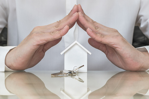 Home buyer protection planning concept with house key in insurance broker agent's hand coverage or in salesman person