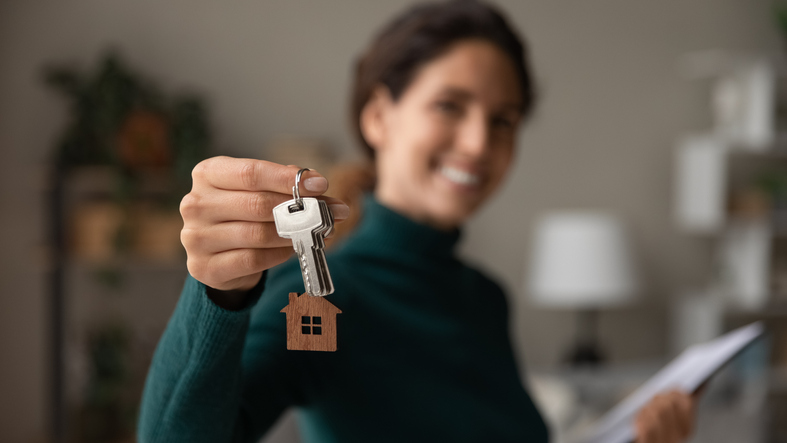 Close up focus on keys, smiling woman Real Estate Agent selling apartment, offering to client, showing at camera, holding documents, contract, making purchasing deal, real estate agent, mortgage or rent