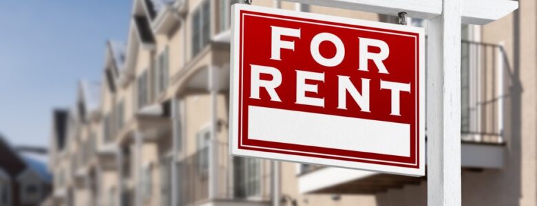 For rent sign in front of apartment buildings, related to US rental market trends and housing demand.